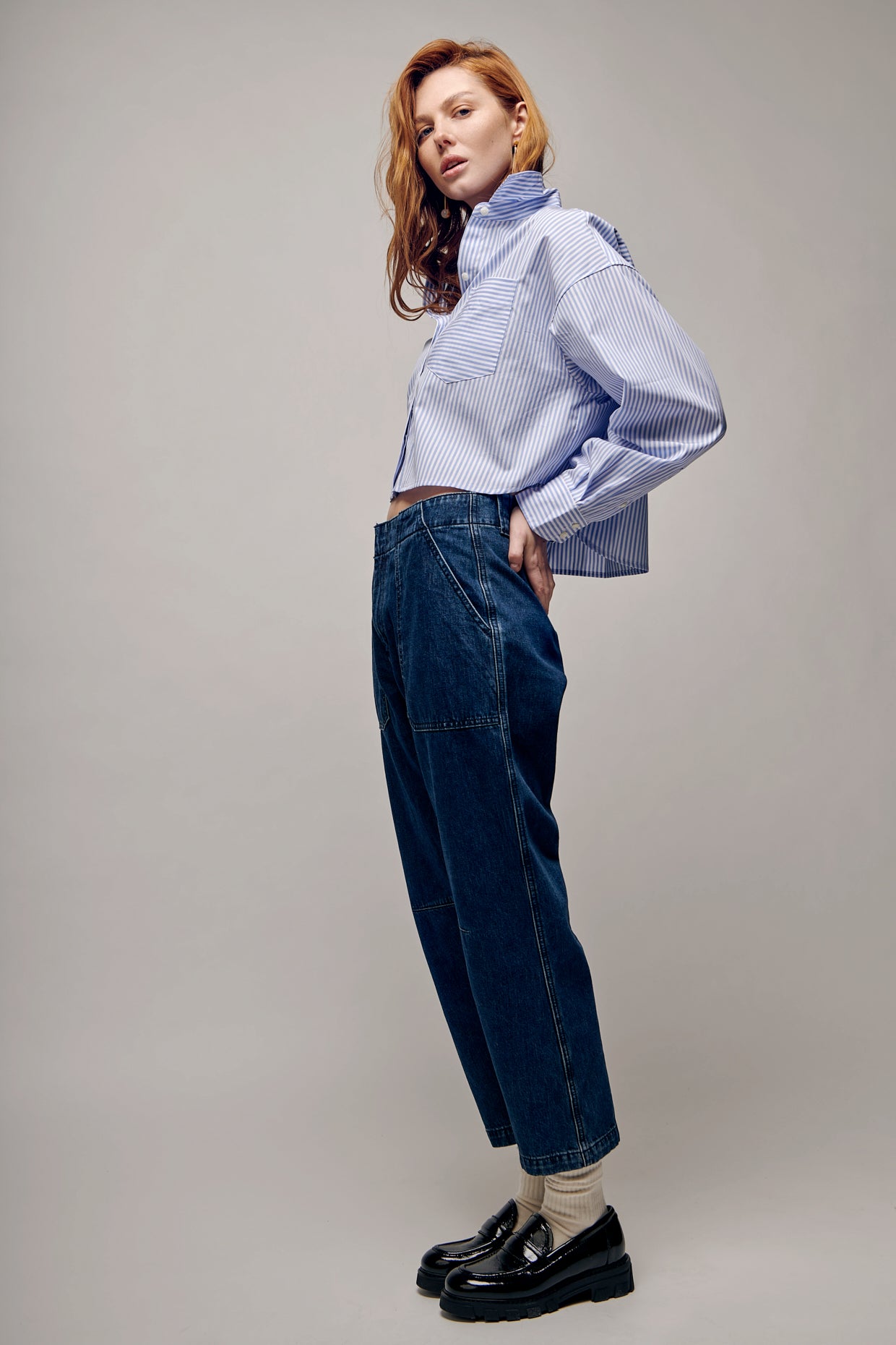 Woman wearing a Rag and Bone blue and white striped blouse with a relaxed fit, classic collar, and cropped length. Paired with Rag and Bone denim work pants featuring a straight-leg silhouette, an ankle crop and functional pockets. Effortlessly stylish ensemble perfect for a casual day at the office or weekend outings.
