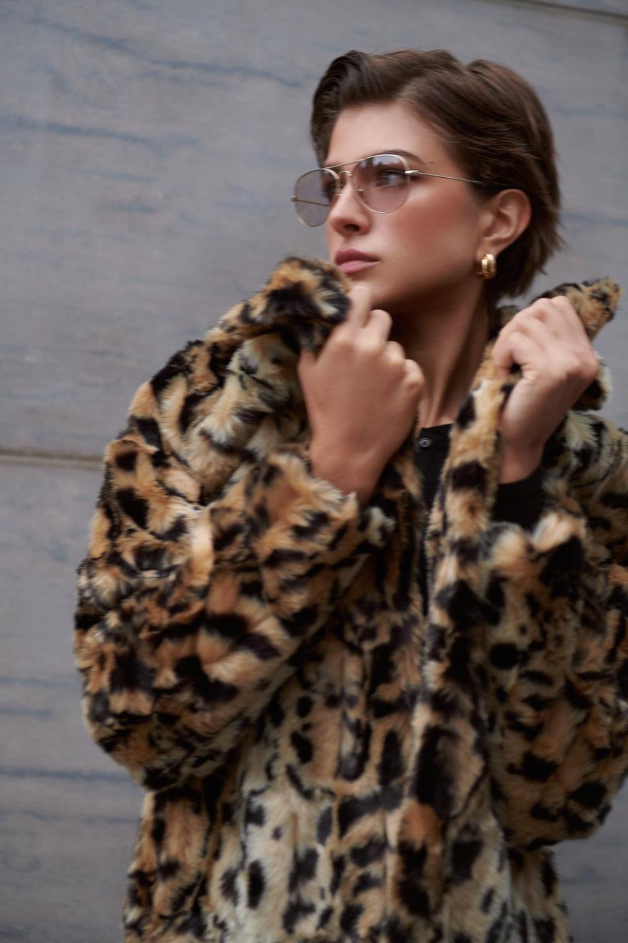 The The Long Song Coat by Unreal Fur accessorized with Mabuhay Matte Gold Reading Glasses and the Florence Earrings by Jenny Bird