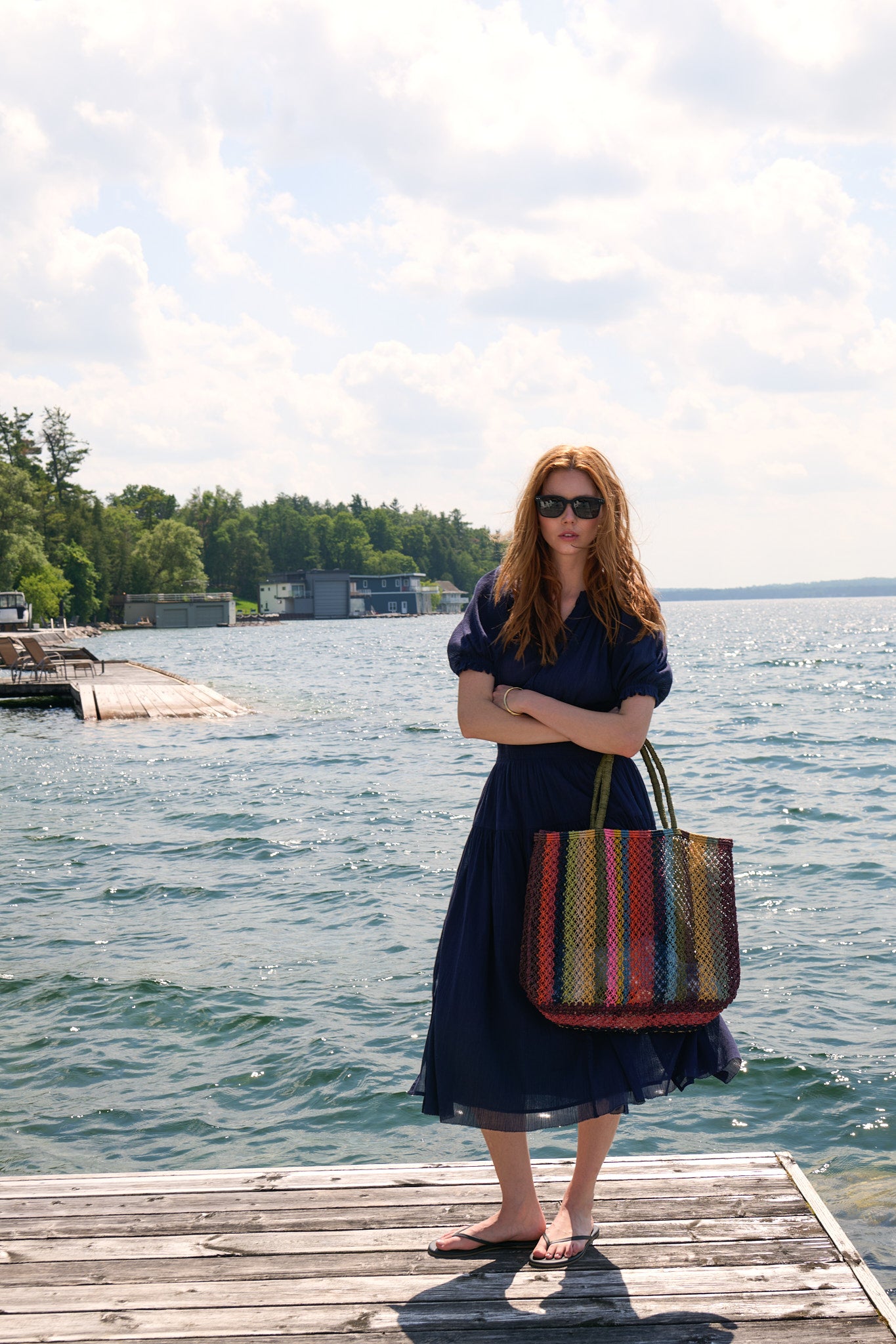 Model in a navy Apiece Apart dress and striped tote on a Muskoka dock for ANDREWS