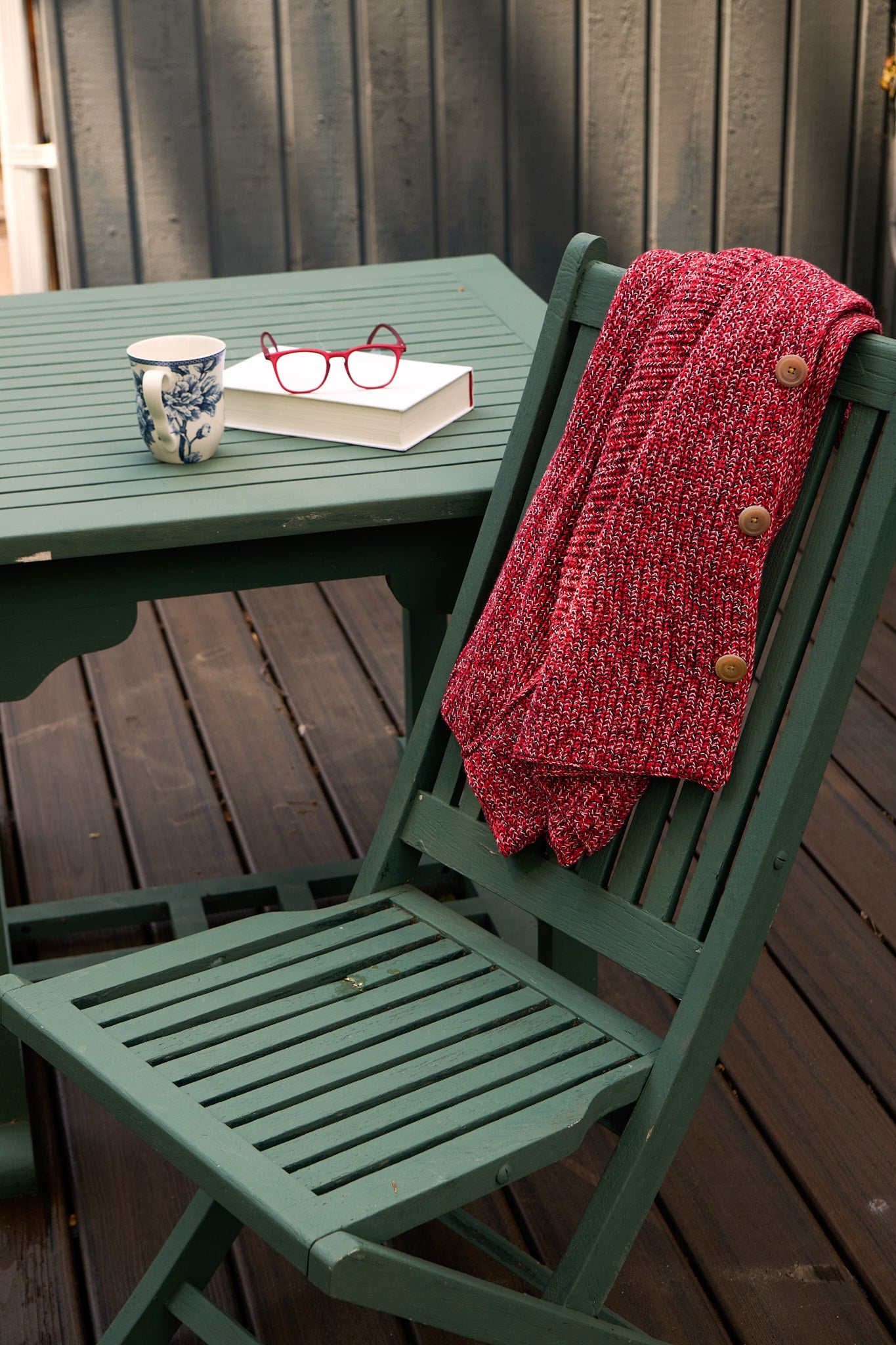 Frank & Eileen cardigan draped over a chair beside red glasses, a book and coffee