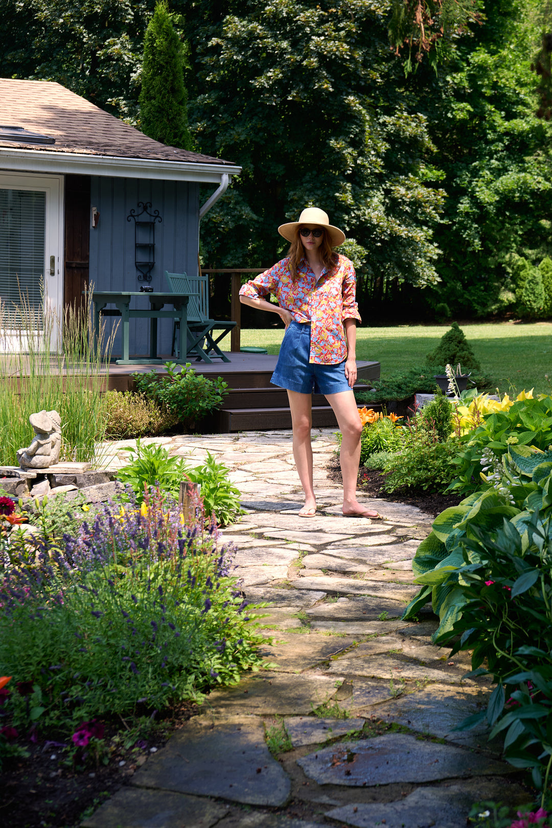 Model in a floral Frank & Eileen shirt, denim shorts and peacoat standing in a Muskoka garden