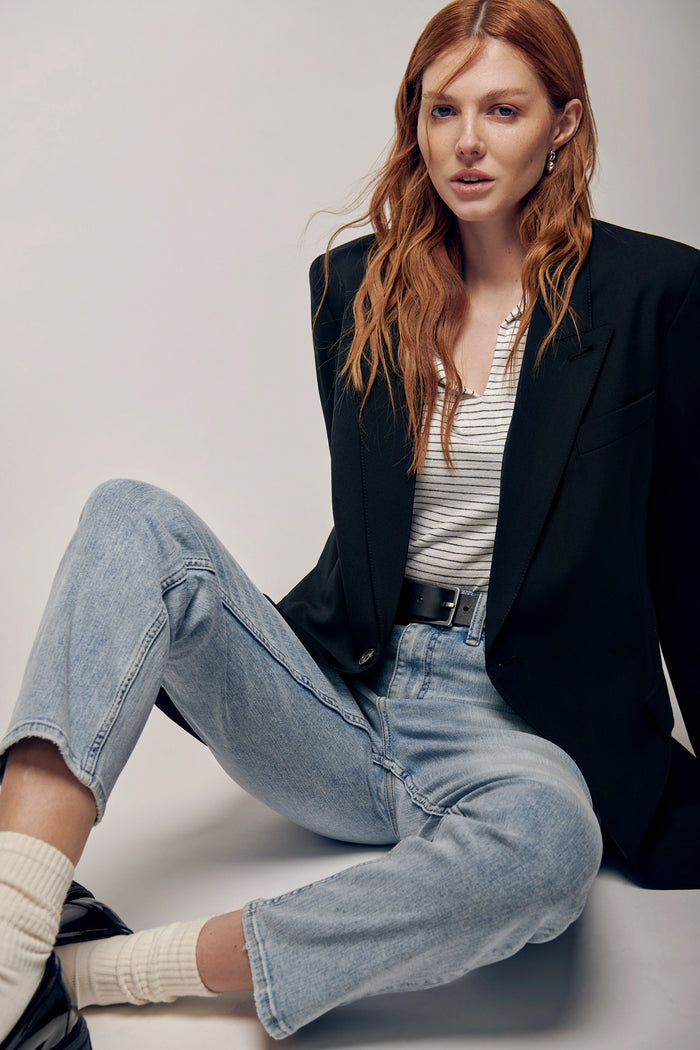 Woman wearing a rag & bone knit polo in off-white and navy blue. Paired with light wash denim jeans and a black leather belt from Rag & bone. Layered with a black Smythe oversize blazer. Styled with black loafers and dress socks. Effortlessly sophisticated ensemble perfect for a casual business.